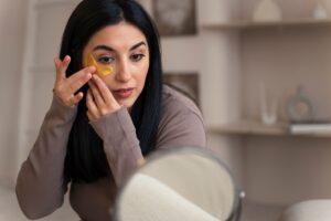 Woman using golden under-eye patches for dark circles treatment and skincare routine